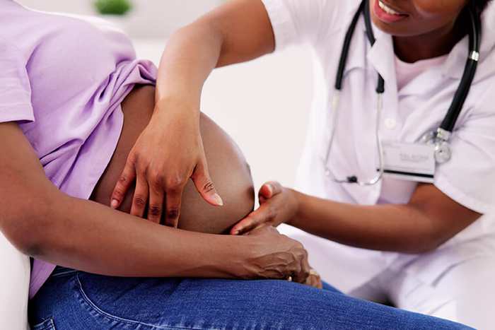 A doctor examining a pregnant patient's belly during an antenatal checkup