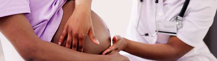A doctor examining a pregnant patient's belly during an antenatal checkup